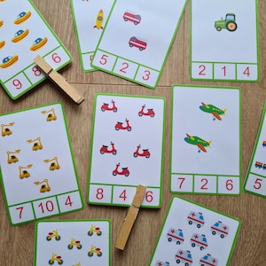 May include: A set of ten colorful flashcards with images of various vehicles and numbers. Each card has a different vehicle, such as a car, truck, airplane, and scooter, and a number corresponding to the number of vehicles on the card. The numbers are written in a bold, black font.