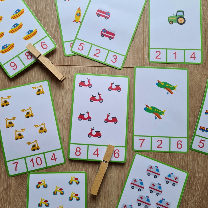 May include: A set of ten colorful flashcards with images of various vehicles and numbers. Each card has a different vehicle, such as a car, truck, airplane, and scooter, and a number corresponding to the number of vehicles on the card. The numbers are written in a bold, black font.