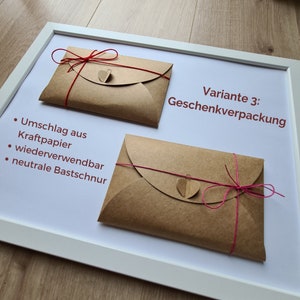 May include: Two brown paper envelopes with red and pink string tied around them. The envelopes have a small heart-shaped tag attached to the string. The text "Variante 3: Geschenkverpackung" is visible in the top right corner of the image.