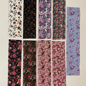 May include: Ten strips of nail art decals with various floral patterns. The patterns include pink, blue, black, and white floral designs.