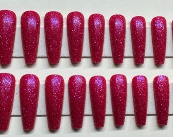 May include: A set of 24 long, coffin-shaped false nails with a pink glitter finish.