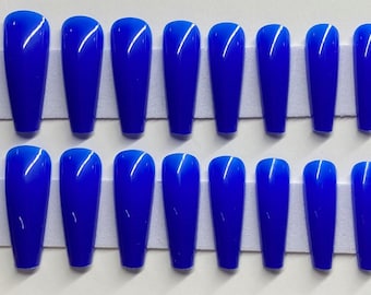 May include: Twenty-four blue coffin-shaped false nails arranged in two rows on a white surface.