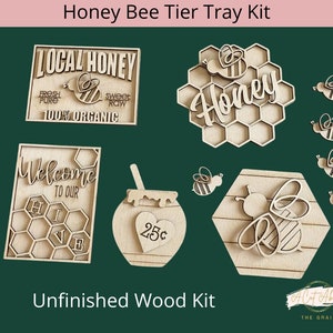 May include: Unfinished wooden Honey Bee Tier Tray Kit. Includes signs with text "Local Honey", "Welcome to our Hive", and "Honey". Also includes a honey pot, bees, and a honeycomb design. The kit is ready to be painted or stained.