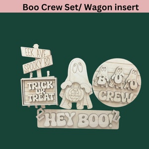 May include: Wooden Halloween decorations with a ghost holding a pumpkin, a sign that says "Trick or Treat", a sign that says "EEK AVE SPOOKY RD", and a sign that says "BOO CREW" with three ghosts. The bottom sign says "HEY BOO!"