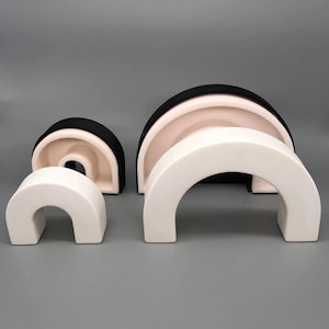 Può includere: Tre archi in ceramica di diverse dimensioni, il più grande è bianco e nero, il medio è rosa e bianco, e il più piccolo è bianco.