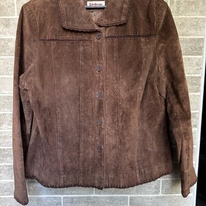 May include: A brown suede jacket with a button-up front and a collar. The jacket features decorative stitching along the seams and around the collar and hem. The label reads "Kaleidoscope".