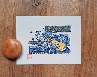 May include: A woodcut print titled "Tea Time" depicts a cat resting near a table with a teacup. The print is in shades of blue and yellow, with a wooden bottle stopper to the left. The print has a red stamp and the artist's signature.