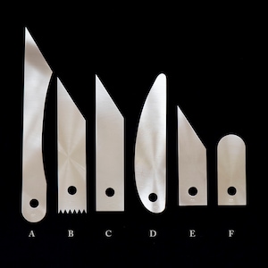 Op de afbeelding: Zes verschillende metalen gereedschappen in verschillende vormen en maten. Elk gereedschap heeft een gat bovenaan en een letterlabel eronder: A, B, C, D, E en F.