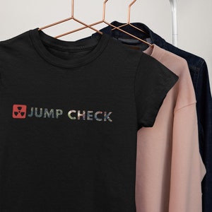 May include: Black t-shirt with a colorful graphic of a radiation symbol and the text "JUMP CHECK".