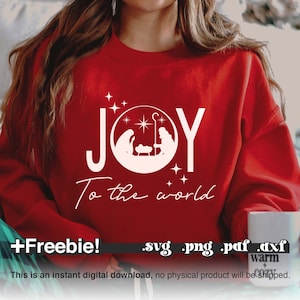 May include: White text on a red sweatshirt reads "JOY to the world" with a white silhouette of the nativity scene inside a circle. The text "Freebie!" and file types ".svg .png .pdf .dxf" are below the design.