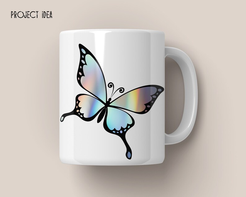 May include: White ceramic mug with a black and iridescent butterfly design. The butterfly has a blue, green, and purple iridescent sheen.
