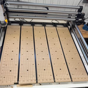 May include: Four wooden panels with a grid pattern and holes drilled in a regular pattern. The panels are marked with numbers along the edges, indicating inches.