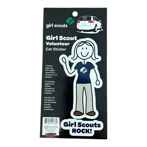May include: A black and white sticker featuring a stick figure of a Girl Scout volunteer wearing a blue shirt with the Girl Scout logo. The sticker says "Girl Scout Volunteer Car Sticker" and "Girl Scouts ROCK!"