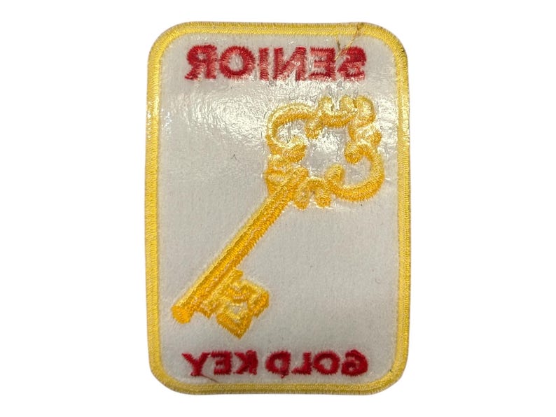 May include: A white patch with a gold key design and the text "GOLD KEY SENIOR" in red.