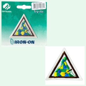 May include: Iron-on patch for Girl Scouts featuring a triangular design with a green, yellow, and blue pattern. The patch says "Try-Its" and "Stach It Together" on the packaging.