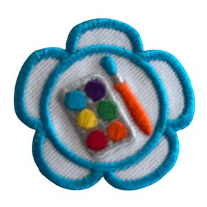 May include: A blue flower-shaped patch with a white center. The center features a paintbrush and a palette of colorful paints.
