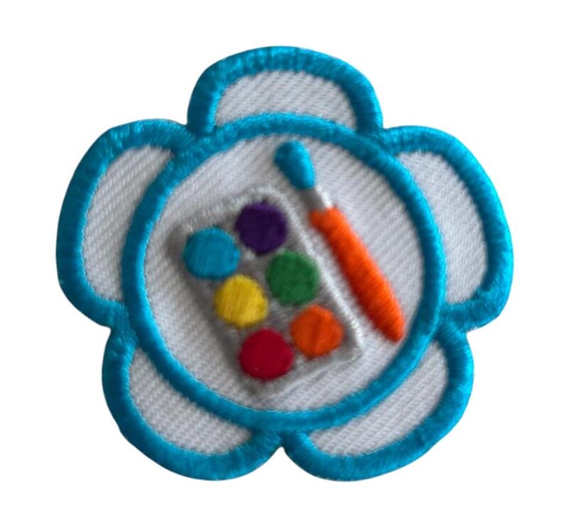 May include: A blue flower-shaped patch with a white center. The center features a paintbrush and a palette of colorful paints.