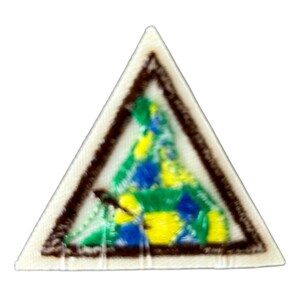 May include: A triangular scout patch with a brown border and a colorful embroidered design inside. The design features a green, blue, and yellow pattern.
