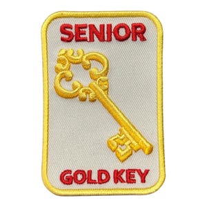 May include: A white patch with a yellow border, featuring a gold key and the text "SENIOR GOLD KEY" in red.