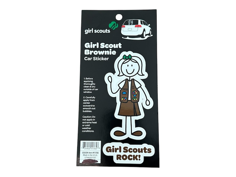 May include: A white car sticker featuring a stick figure of a Girl Scout Brownie wearing a brown uniform and a green sash with badges. The text "Girl Scouts ROCK!" is printed below the figure.