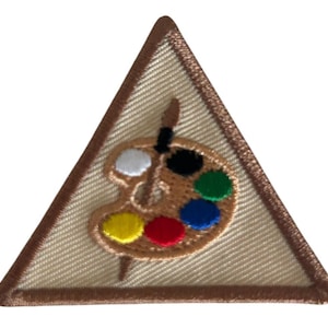 May include: A triangular-shaped Girl Scout patch with a brown border. The patch features a paint palette with a paintbrush, and the colors on the palette are white, black, yellow, red, blue, and green.