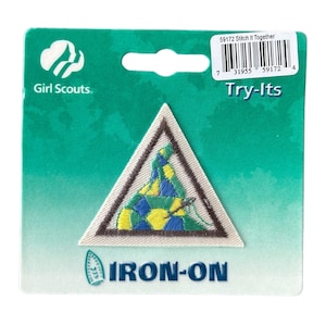 May include: Girl Scout Try-Its iron-on patch featuring a triangular design with a colorful, stitched-together quilt inside. The patch is brown, white, green, yellow, and blue.