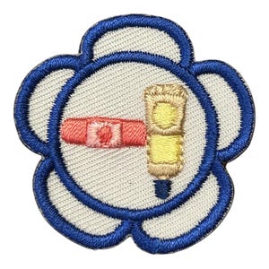 May include: A blue and white embroidered flower patch with a pink and yellow tube of hand cream inside.