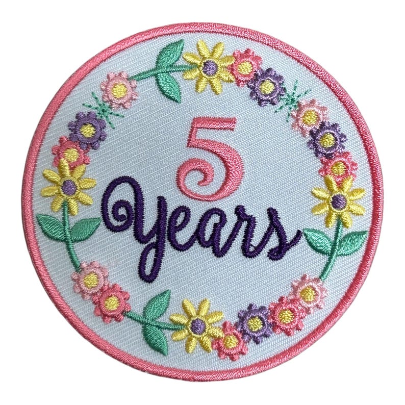 May include: Embroidered patch with a light blue background, featuring the number "5" and the word "Years" in pink and purple script. A wreath of colorful flowers in yellow, pink, and purple surrounds the text, with a pink border.