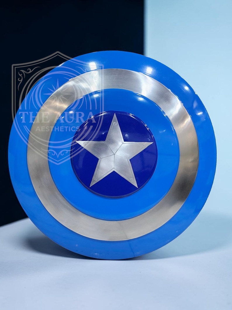 May include: A blue and silver shield featuring a white star at its centre. The shield has concentric circles of blue and silver. The text "THE AURA AESTHETICS" is visible on the shield.