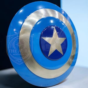 May include: A blue and silver shield with a central star design. The shield features concentric circles of blue and silver, with a star at the centre. The text "THE AURA AESTHETICS" is visible on the left side of the shield.