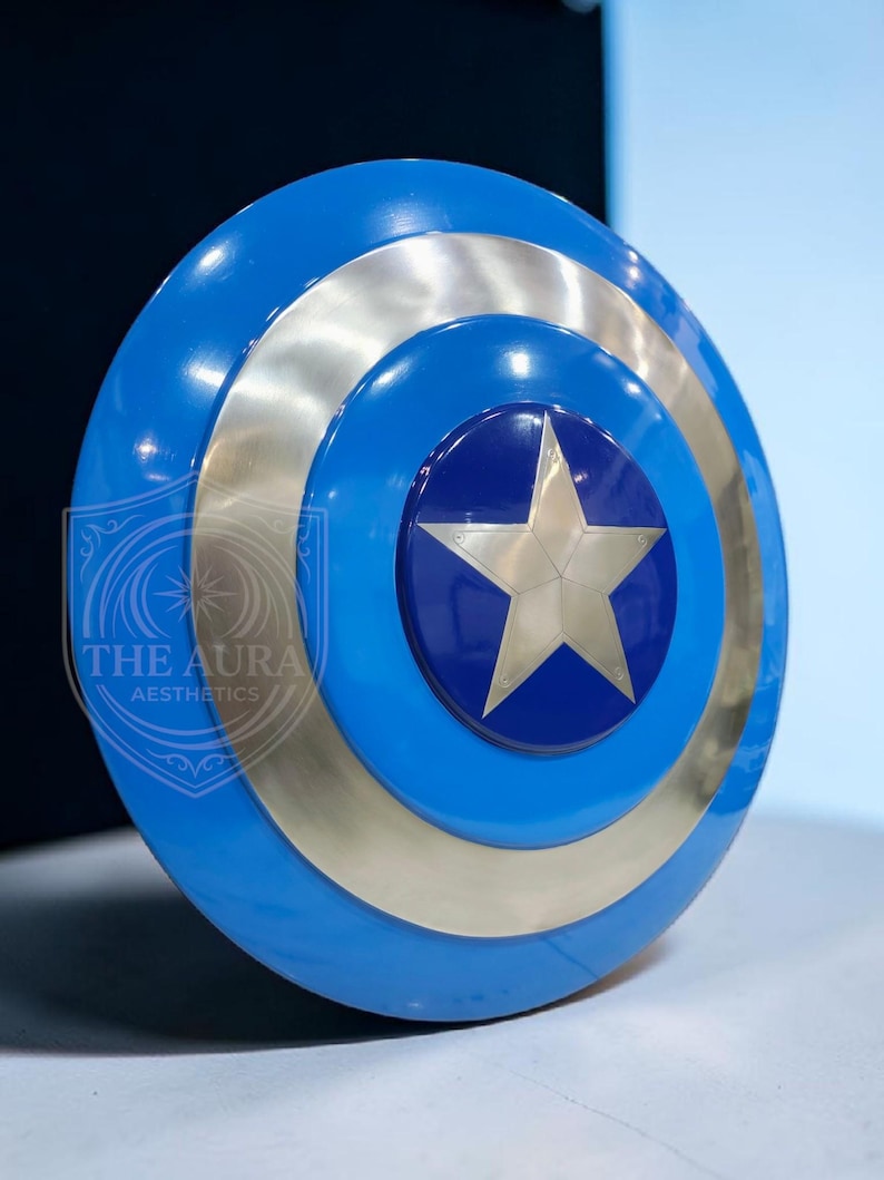 May include: A blue and silver shield with a central star design. The shield features concentric circles of blue and silver, with a star at the centre. The text "THE AURA AESTHETICS" is visible on the left side of the shield.