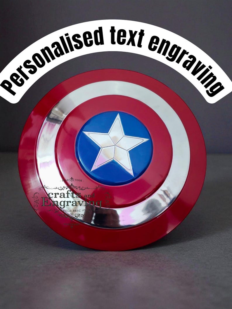 May include: A red, white, and blue shield with a silver rim and a white star on a blue center. The shield has the text "Personalised text engraving" in a white arch. The shield is a replica of a superhero's shield.