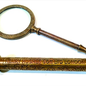 May include: A brass magnifying glass with a handle engraved with "HENRY HUGHES SON LTD LONDON 1941".