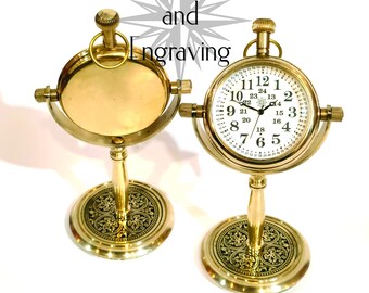 May include: A brass clock with a white face and black numbers. The clock is on a decorative stand with an ornate design. The clock is a decorative item and is not functional.