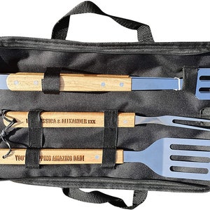 May include: A black zippered carrying case with a handle, containing a set of three grilling tools with wooden handles. The handles are engraved with the text "You're an Amazing Dad!" and "Jessica & Alexander XXX".
