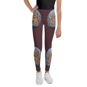 Puede incluir: Un par de leggings color marrón oscuro con un patrón repetido de una puerta azul y marrón con enredaderas y setas. Las leggings están en una persona que lleva zapatillas blancas.