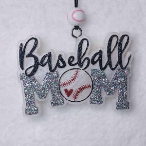 May include: A silver glitter car charm with the words "Baseball Mom" and a white baseball with red stitching and a red heart.