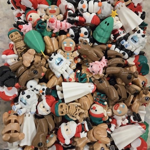 May include: A collection of Christmas-themed figurines, including Santa Claus, snowmen, reindeer, gingerbread men, penguins, and Christmas trees. The figurines are in various colors, such as red, white, brown, green, and black. Some figurines have a skeleton design.