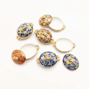 May include: Set of six miniature porcelain serving dishes with lids. The dishes are oval shaped and feature intricate floral designs in shades of blue, red, and gold. The lids have a small knob on top.