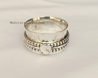 Può includere: Un anello rotante in argento con un design a forma di cuore. L'anello ha tre bande con bordi testurizzati.