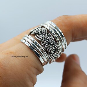 Könnte beinhalten: Ein silberner Ring mit einem geflochtenen Mittelteil und mehreren Bändern. Der Ring hat eine strukturierte Oberfläche und wird an einem Finger getragen. Der Text "Silverjewellery30" ist im Bild zu sehen.