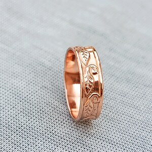 Pu&ograve; includere: Un anello in oro rosa con un motivo a foglie incise. L'anello ha una finitura lucida e una larghezza della fascia di circa 0,6 cm. Il design presenta elementi botanici dettagliati.