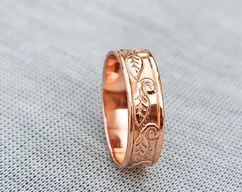 Könnte beinhalten: Ein roségoldener Ring mit einem eingravierten Blattmuster. Der Ring hat eine polierte Oberfläche und eine Bandbreite von ca. 0,6 cm. Das Design zeigt detaillierte botanische Elemente.