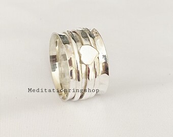 Può includere: Anello girevole in argento con un design a forma di cuore. L'anello è composto da più bande che ruotano l'una intorno all'altra.