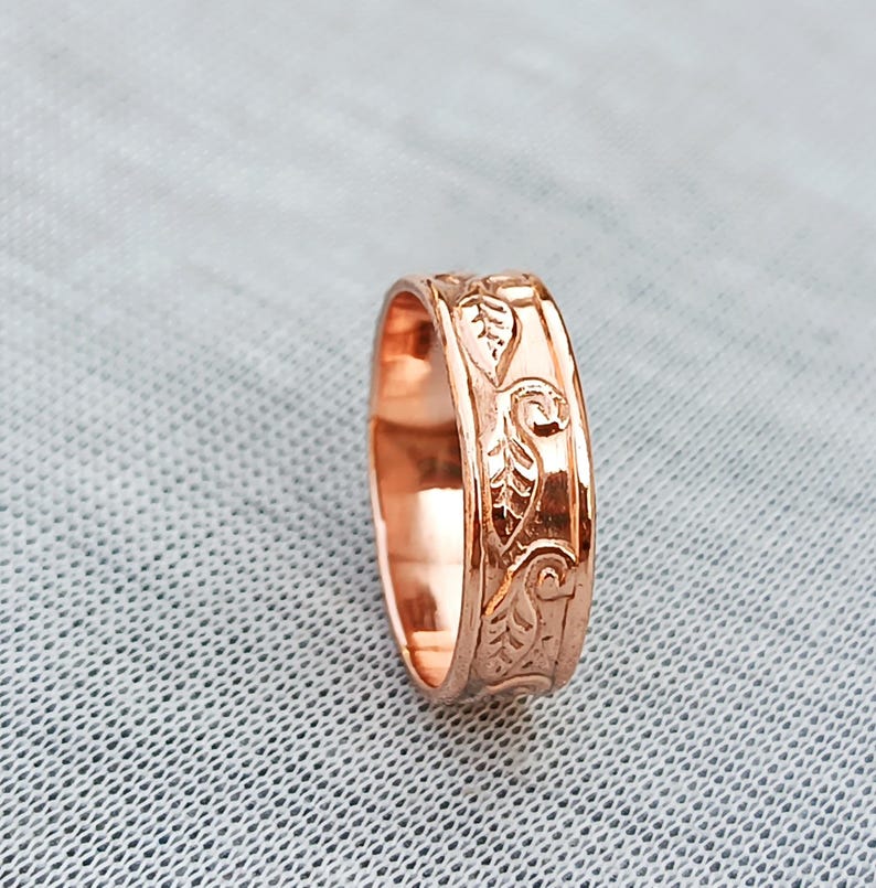 Pu&ograve; includere: Un anello in oro rosa con un motivo a foglie inciso. L'anello ha una finitura lucida e una larghezza della fascia di circa 0,64 cm. Il design presenta dettagliati motivi di foglie e viti.