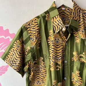 May include: A green and brown striped button-up shirt with a tiger print. The shirt has a collar and short sleeves.
