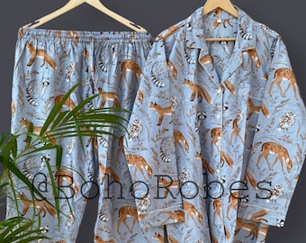 May include: A blue pajama set with a woodland animal print featuring deer, foxes, and owls. The set includes a long-sleeved shirt with a button-up collar and matching pants.