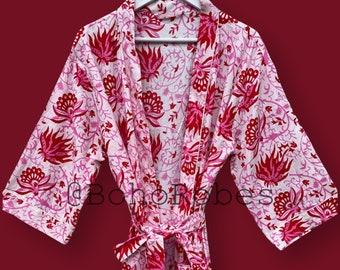 Könnte beinhalten: Eine rosa und rote Baumwollrobe mit floralem Muster und einem Bindegürtel. Die Robe hat einen traditionellen japanischen Kimono-Stil.