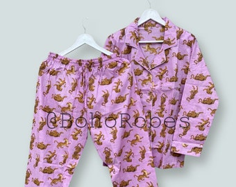May include: A purple pajama set with a long-sleeved shirt and pants. The fabric features a repeating pattern of orange tigers on a light purple background.