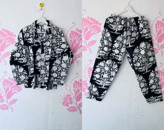May include: Black and white printed pajama set with a floral pattern. The top is a long-sleeved shirt with a collar and the pants are loose-fitting.